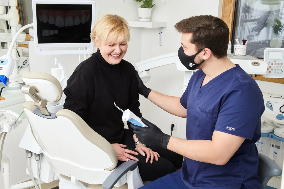 A dentist sitting beside a patient in conversation, both of them laughing