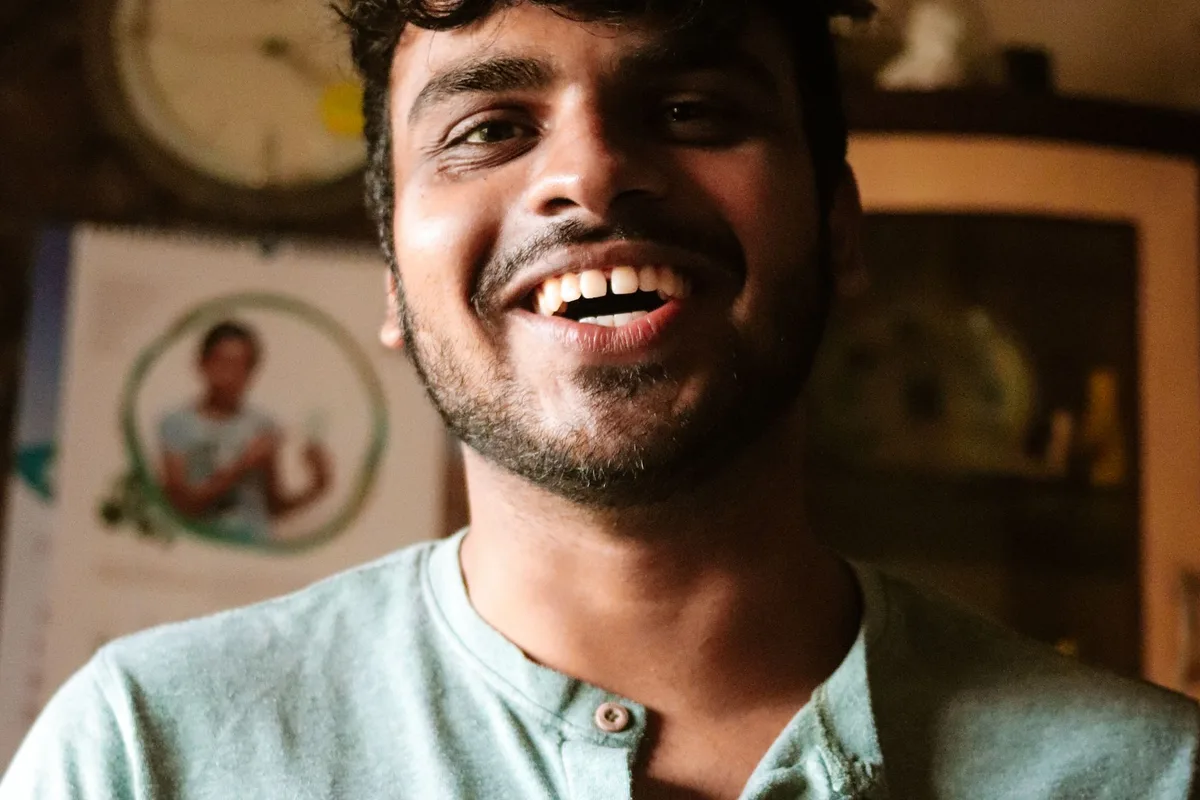 A man in a green shirt laughing, lit by warm indoor light